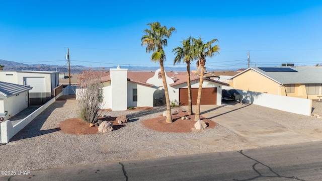 view of front of house featuring stucco siding, fence, a residential view, concrete driveway, and an attached garage