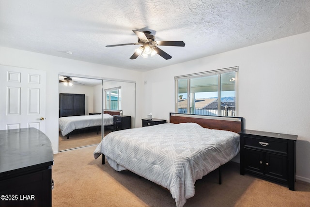 bedroom with multiple windows, light carpet, a textured ceiling, and a closet