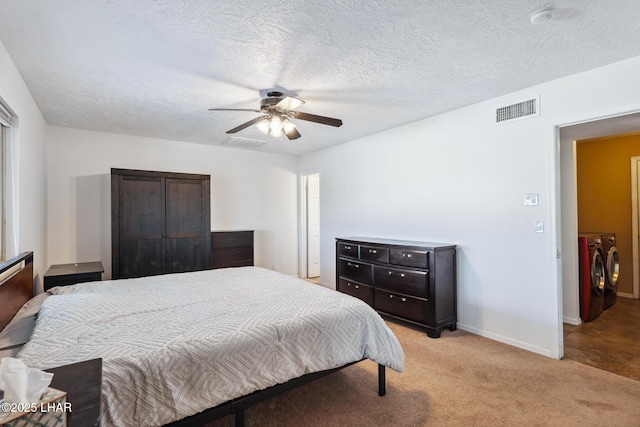 bedroom with independent washer and dryer, ceiling fan, visible vents, and light carpet