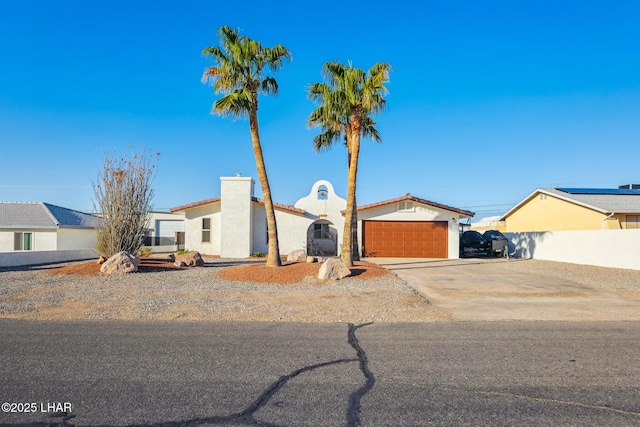 view of front of house with concrete driveway, an attached garage, fence, and stucco siding