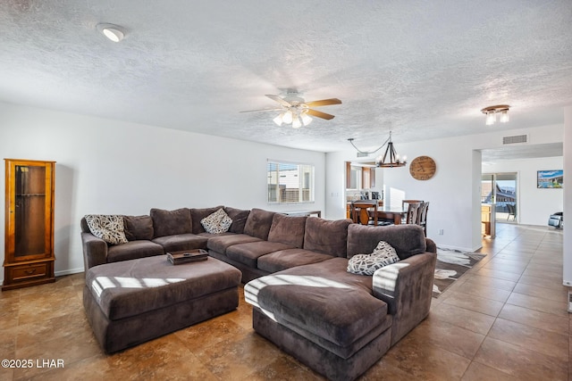 living room with visible vents, a textured ceiling, and ceiling fan with notable chandelier