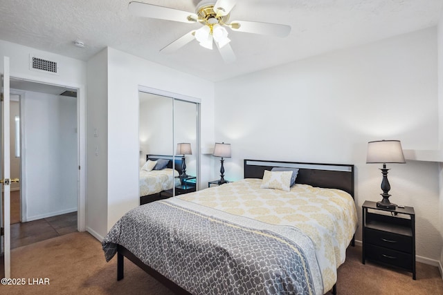 carpeted bedroom with visible vents, baseboards, ceiling fan, a closet, and a textured ceiling