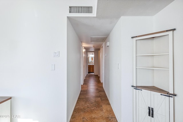 hall featuring visible vents, baseboards, and a textured ceiling