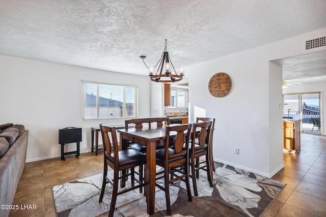 dining area featuring tile patterned floors, baseboards, visible vents, and a textured ceiling