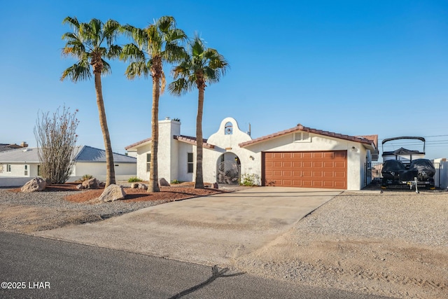 mediterranean / spanish house featuring stucco siding, a chimney, concrete driveway, and an attached garage