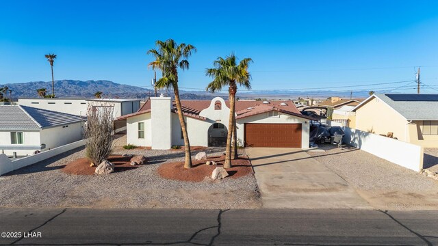 view of front facade featuring fence, driveway, an attached garage, a residential view, and a mountain view