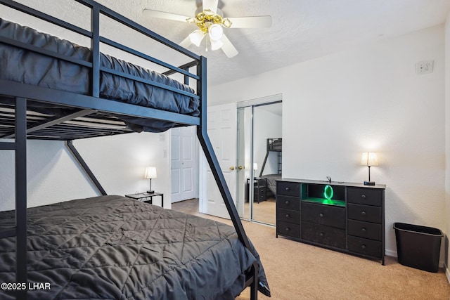 carpeted bedroom with a ceiling fan, a closet, and a textured ceiling