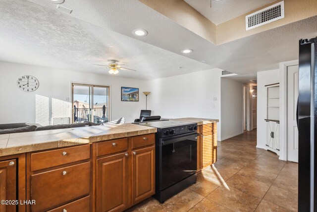 kitchen featuring a ceiling fan, visible vents, black appliances, a textured ceiling, and brown cabinets