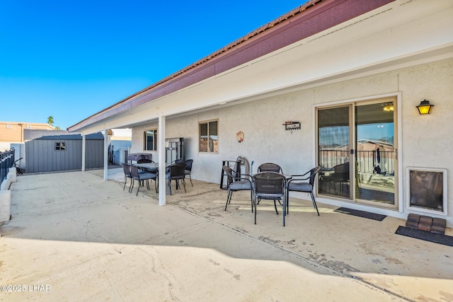 view of patio / terrace with an outdoor structure, outdoor dining area, and a storage unit