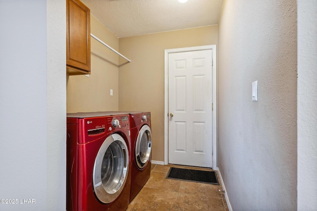 clothes washing area with washer and dryer, baseboards, cabinet space, and a textured ceiling