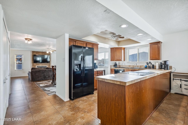 kitchen featuring a tray ceiling, black appliances, a peninsula, and a ceiling fan