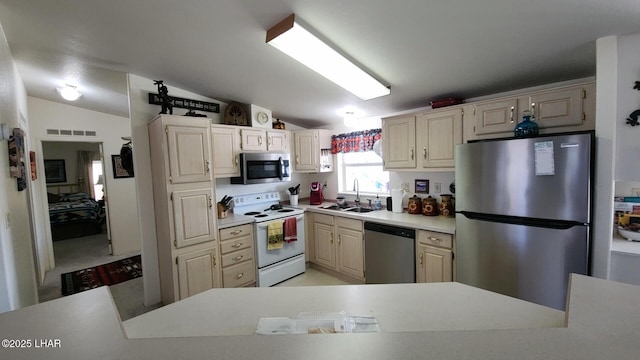 kitchen featuring light countertops, a sink, appliances with stainless steel finishes, lofted ceiling, and visible vents