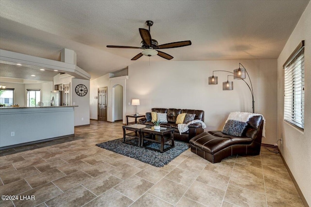 living room featuring ceiling fan, vaulted ceiling, and a textured ceiling