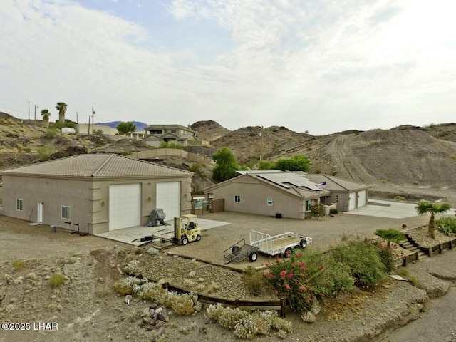 back of house with stucco siding, a tiled roof, a garage, and a mountain view