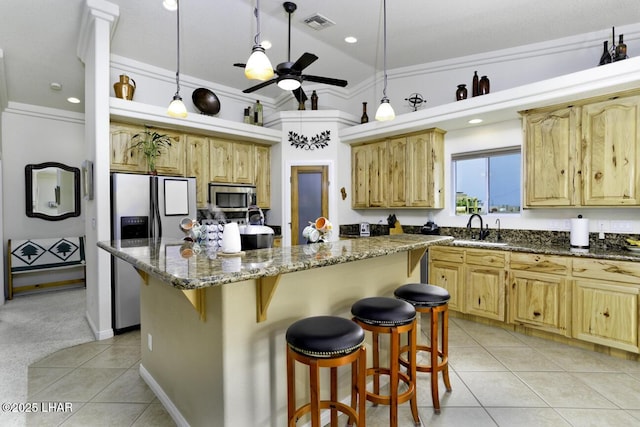 kitchen featuring a sink, a breakfast bar area, appliances with stainless steel finishes, and light tile patterned flooring