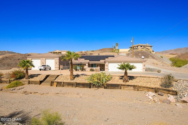 view of front of house with driveway, an attached garage, a fenced front yard, a tile roof, and a mountain view