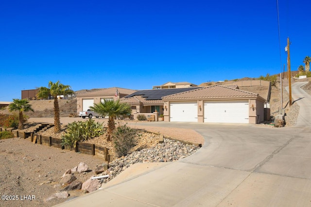 view of front of house featuring stucco siding, a tile roof, roof mounted solar panels, concrete driveway, and a garage