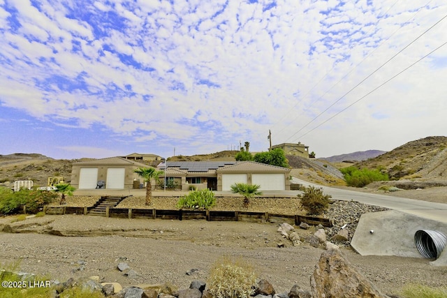 view of front of home featuring a mountain view, a garage, and solar panels