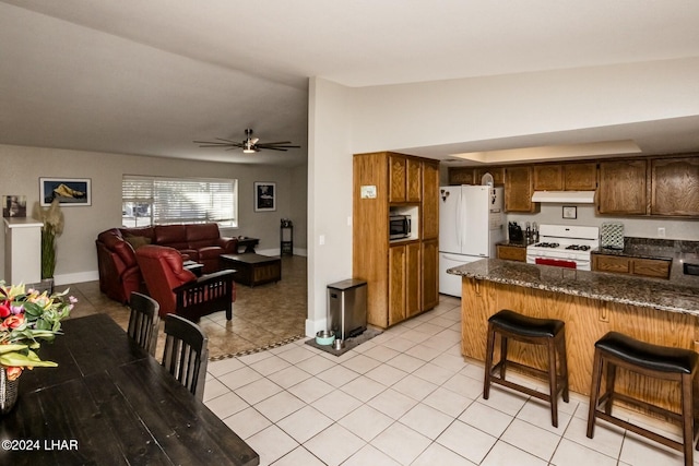 kitchen featuring light tile patterned floors, white appliances, ceiling fan, a kitchen breakfast bar, and kitchen peninsula