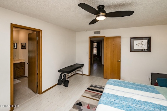 bedroom featuring a textured ceiling, light wood finished floors, visible vents, and baseboards