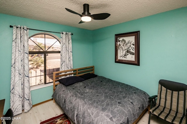 bedroom featuring multiple windows, a textured ceiling, and wood finished floors