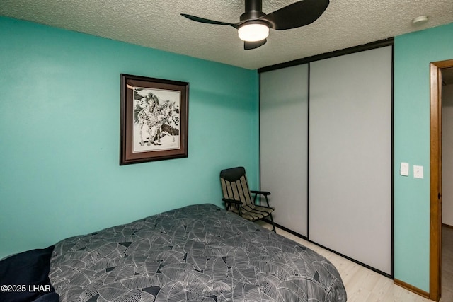 bedroom with a closet, ceiling fan, a textured ceiling, and wood finished floors