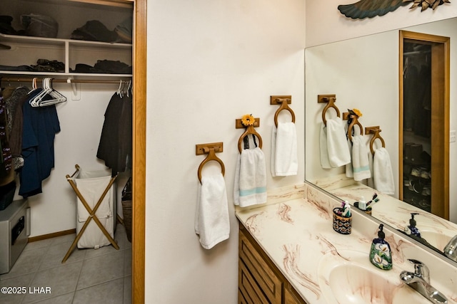 bathroom featuring tile patterned flooring, a walk in closet, and vanity