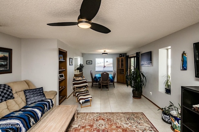 living area featuring a ceiling fan, a textured ceiling, and light tile patterned floors