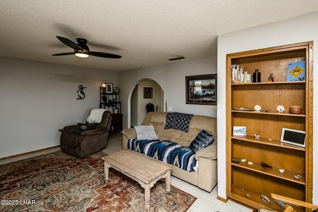 living room with visible vents, a textured ceiling, arched walkways, and a ceiling fan