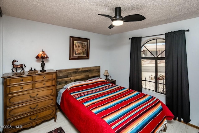 bedroom featuring ceiling fan, light wood-style flooring, and a textured ceiling