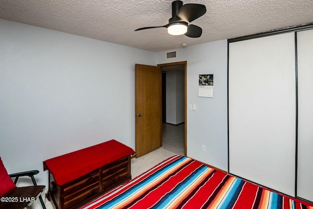 bedroom featuring a textured ceiling, a closet, visible vents, and a ceiling fan