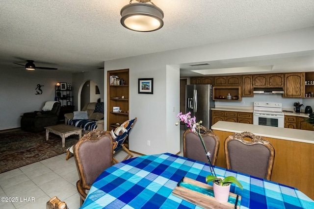 dining area featuring arched walkways, a textured ceiling, light tile patterned flooring, and visible vents