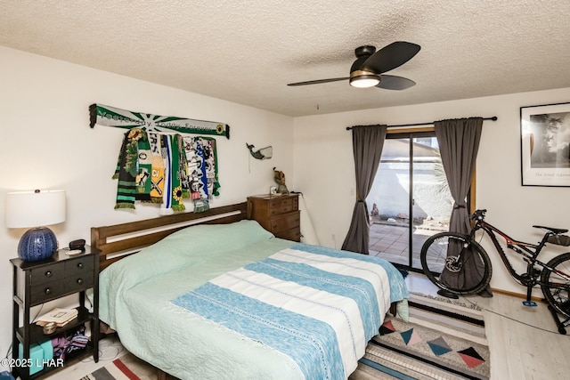 bedroom with a textured ceiling, wood finished floors, a ceiling fan, and access to exterior