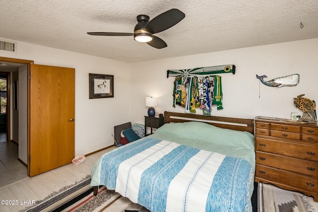 bedroom with a ceiling fan, visible vents, and a textured ceiling