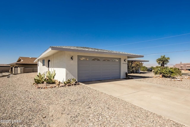 view of side of home featuring a garage, concrete driveway, and stucco siding