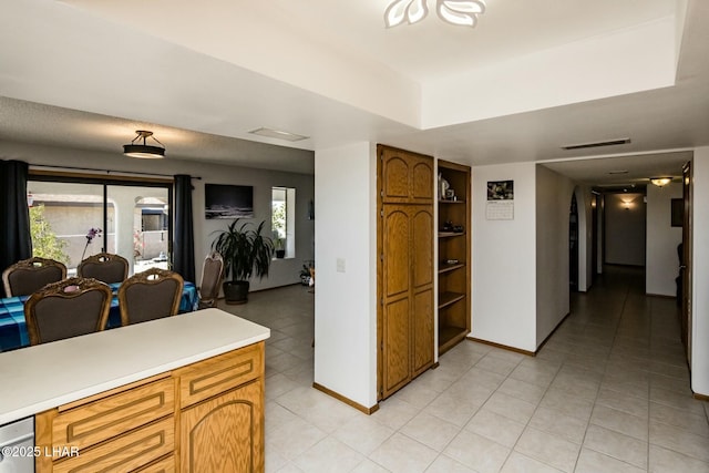 kitchen featuring brown cabinetry, light countertops, visible vents, and baseboards