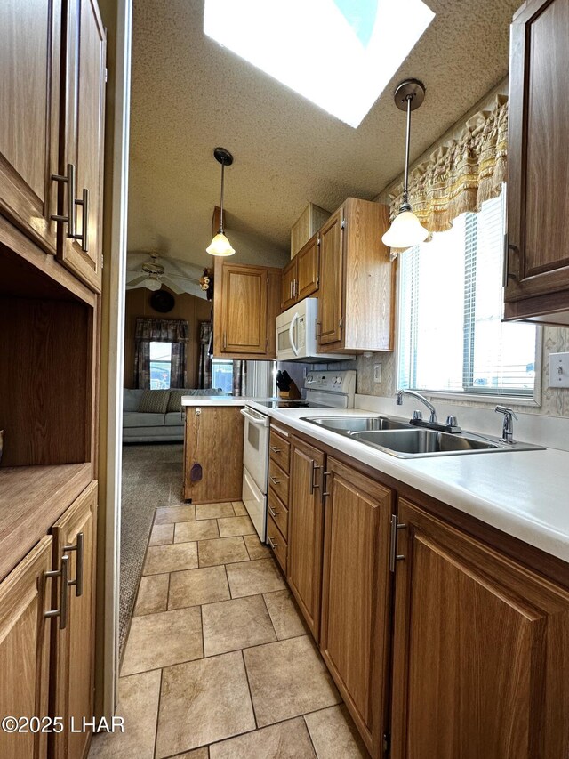 kitchen featuring pendant lighting, ceiling fan, white appliances, and vaulted ceiling with skylight