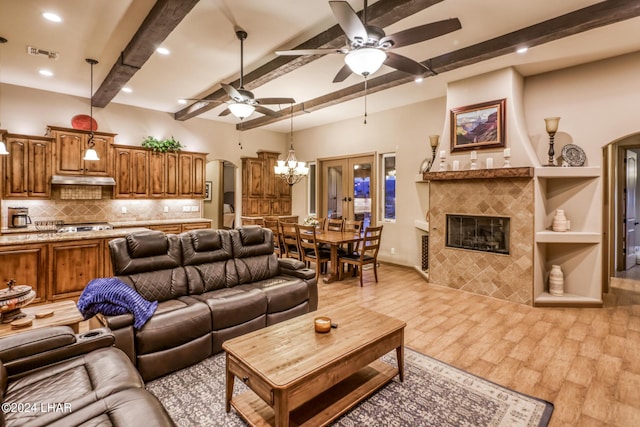 living room featuring visible vents, a fireplace, beamed ceiling, and light wood finished floors