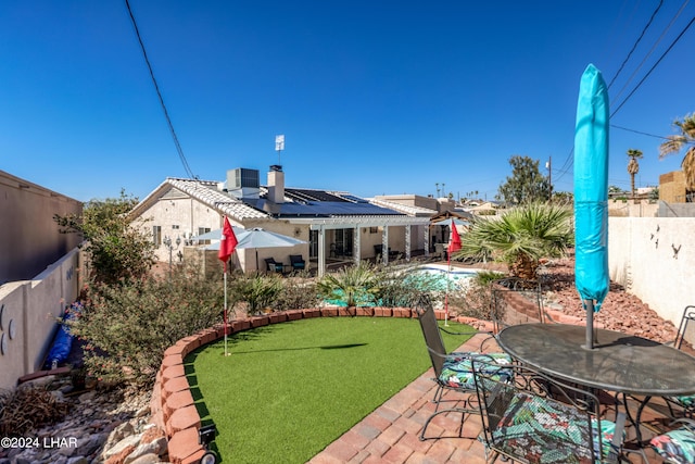 exterior space featuring a fenced in pool, a patio area, and solar panels