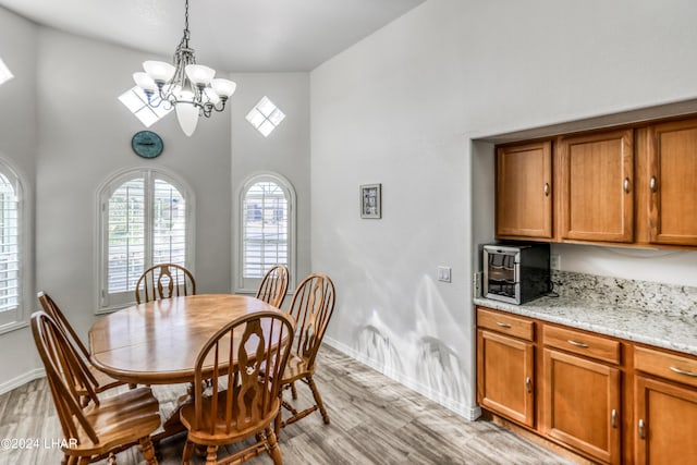 dining area with a towering ceiling, an inviting chandelier, and light wood-type flooring