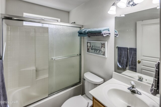 full bathroom with vanity, combined bath / shower with glass door, and toilet