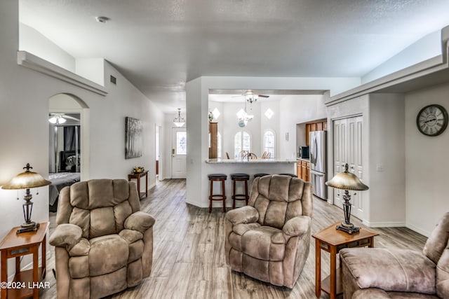 living room featuring ceiling fan, a textured ceiling, and light wood-type flooring