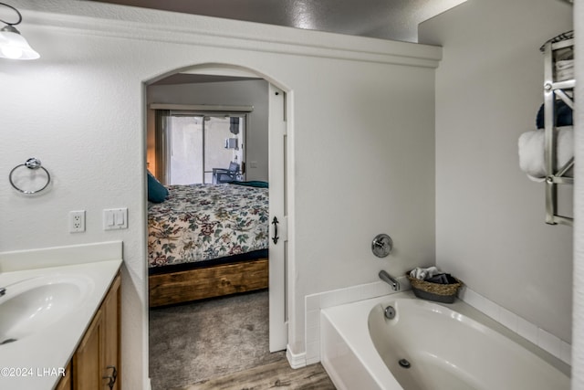 bathroom featuring a washtub, vanity, and hardwood / wood-style flooring