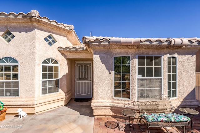 view of exterior entry with a patio