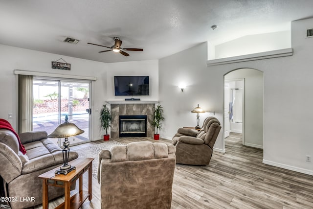 living room featuring lofted ceiling, ceiling fan, a fireplace, and wood-type flooring