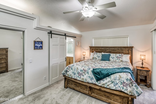 bedroom featuring light carpet, a barn door, and ceiling fan