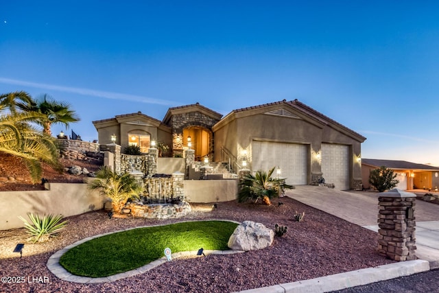 mediterranean / spanish home featuring concrete driveway, stone siding, a tile roof, an attached garage, and stucco siding