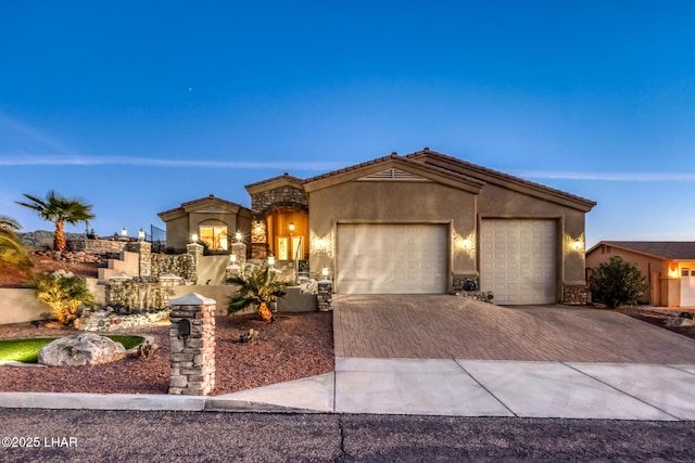 view of front facade with an attached garage, a tiled roof, decorative driveway, and stucco siding