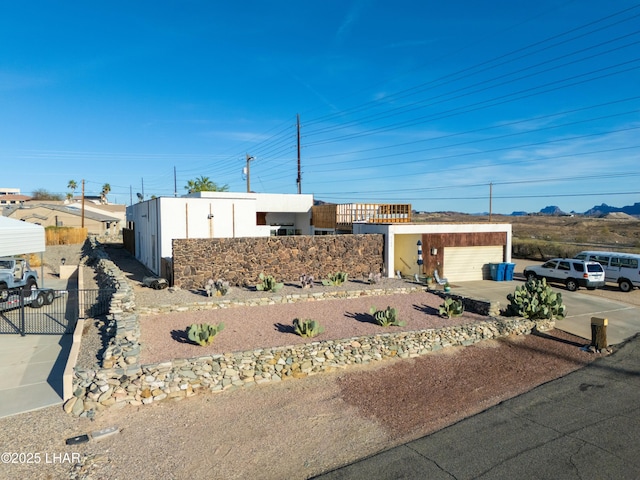 view of front facade featuring stucco siding, an outdoor structure, a garage, and fence