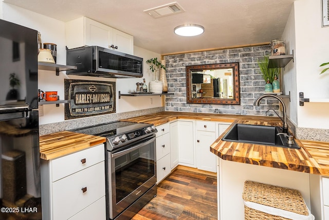 kitchen featuring white cabinetry, wood counters, stainless steel appliances, and sink